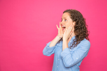 Portrait young girl screaming sideways with hands on face on pink background