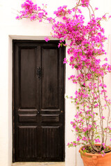 Whitewashed facade with old wooden door and bougainvillea in Altea