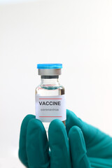Hand wearing gloves holding glass vial containing liquid medical vaccine used to shot for injection treatment on white background, vaccination and immunization care for preventing coronavirus (COVID-1