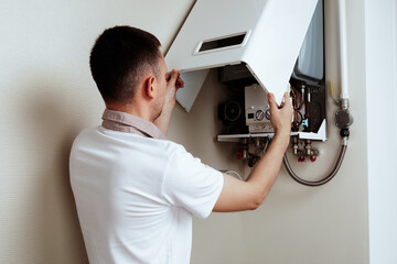 Naklejka na ściany i meble Plumber attaches Trying To Fix the Problem with the Residential Heating Equipment. Repair of a gas boiler