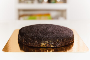 Freshly baked sponge chocolate cake with on golden paper board.