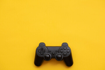 Black video game controller on a bright yellow background