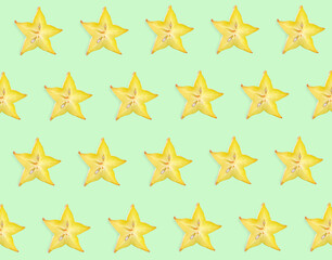 Fototapeta premium Slices of carambola on light green background, flat lay