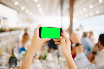 Woman at a wedding banquet filming a party on a smartphone, close-up 
