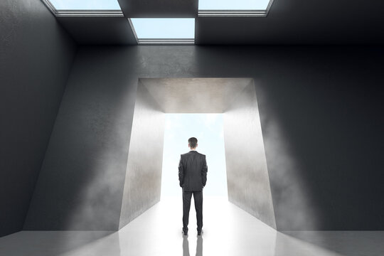 Thoughtful businessman in concrete office room interior standing at success door. New way, start up and innovation concept. - Powered by Adobe