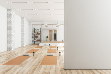 Modern concrete yoga gym interior with equipment, blank mockup space on wall, daylight and wooden flooring. Healthy lifestyle concept. Mock up, 3D Rendering.
