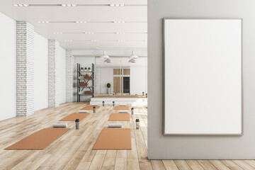 Modern concrete yoga gym interior with equipment, blank banner on wall, daylight and wooden flooring. Healthy lifestyle concept. Mock up, 3D Rendering.