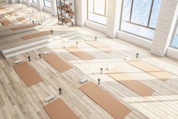 Clean concrete yoga gym interior with equipment, daylight and wooden flooring. Healthy lifestyle concept. 3D Rendering.