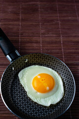 Frying pan with fried egg on a bamboo table