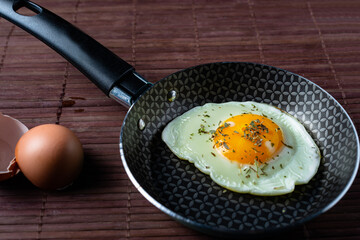 Frying pan with fried egg on a bamboo table