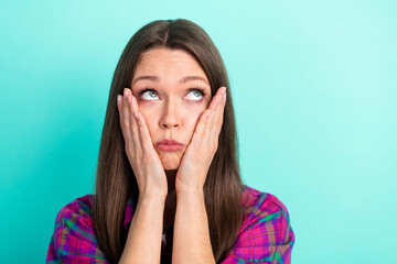 Photo of worried long hairdo young lady look empty space hands face wear checkered shirt isolated on vivid teal color background