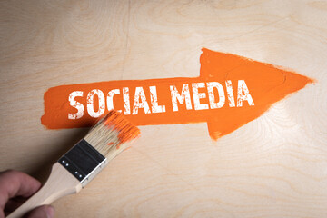 Social Media concept. Orange arrow on a wooden background