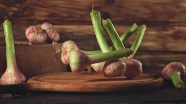 Super slow motion garlic falls on a cutting board on a wooden background. Filmed on a high-speed camera at 1000 fps. High quality FullHD footage
