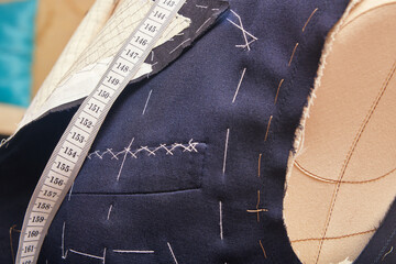 Sewn chest pocket on semi-ready suit jacket. Suit tailoring in process of custom-made jacket. Bespoke suit tailoring in tailor workshop. Working on a made-to-measure suit jacket