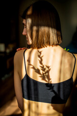Beauty portrait of a back beautiful young girl with a shadow pattern on the face and body in the...