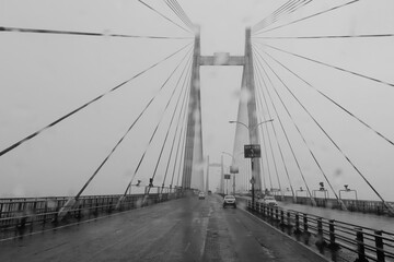 Vidyasagar Setu over river Ganges, known as 2nd Hooghly Bridge in Kolkata,West Bengal, India. Abstract black and white image shot aginst glass with raindrops all over it, monsoon image of Kolkata.