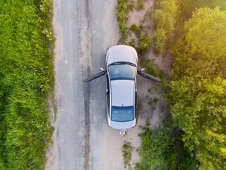 Car with open doors stands on side of rural road, aerial view