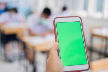 Mock up green screen smart phone, Application digital smartphone on exam testroom while Students school wear face mask learning project searching app in online classroom learners in modern technology