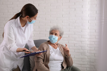 Doctor examining senior woman with protective mask at nursing home