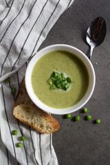 Green vegetable soup in a bowl. Top view photo of vegetarian meal. Homemade green peas creamy soup. Vegetarian menu ideas.  Eating fresh concept. 