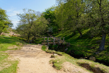 Wide sandy path to a small wooden bridge across Burbage Brook in Derbyshire