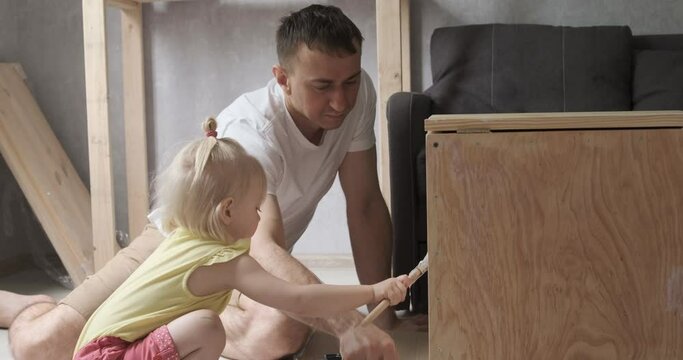Father and little baby girl doing carpentry. Daughter helps dad in carpentry workshop.