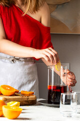 Woman preparing Sangria, Spanish refreshment drink , making with wine and fruits. Summer acholic beverage