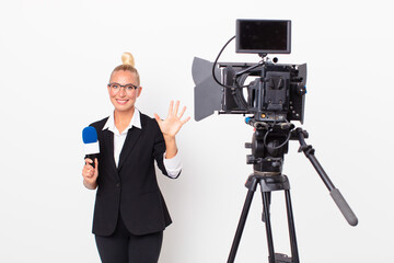 pretty blond woman smiling and looking friendly, showing number five and holding a pmicrophone....