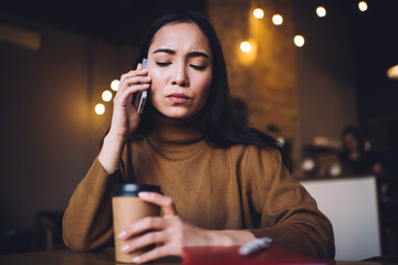 Focused woman talking on phone at cafe