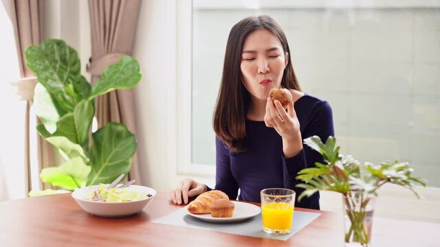 Having meal concept a young woman eating a cupcake as a dessert with orange juice after eating salad at her place.