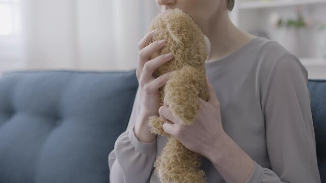 Sad woman looking at teddy bear, suffering loneliness, miscarriage depression