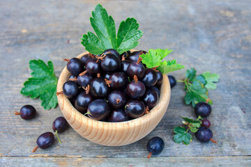 Porzeczkoagrest w drewnianej misce na tle desek © Monika