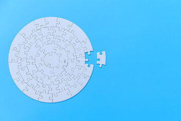 White jigsaw puzzle on a blue background. Completing final task, missing jigsaw puzzle pieces and business concept with a puzzle piece missing. - obrazy, fototapety, plakaty