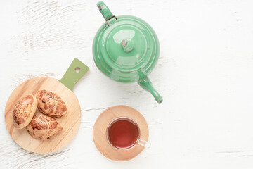 Fototapeta na wymiar homemade pastry buns, glass of tea and teapot on the table