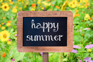 Happy summer sign written on a vintage wooden frame chalkboard, flower in the background