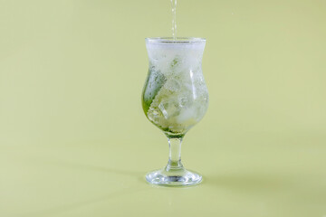 fresh seltzer water is poured into a glass with mint and ice. refreshing drinks in the heat