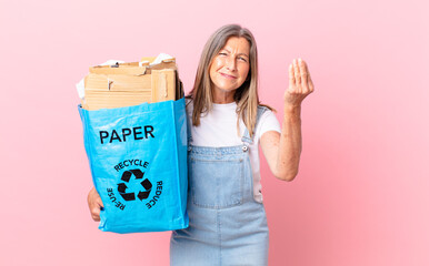 pretty middle age woman making capice or money gesture, telling you to pay recycling cardboard...