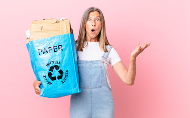 pretty middle age woman amazed, shocked and astonished with an unbelievable surprise recycling...