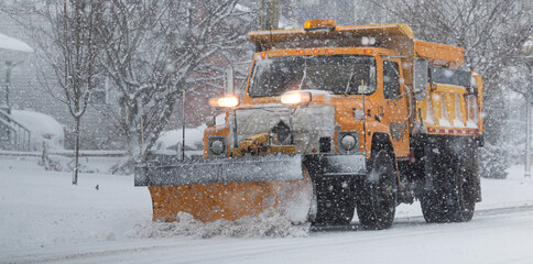 Yellow municipal snow plow plowing during a blizzrd - obrazy, fototapety, plakaty