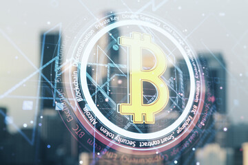 Double exposure of creative Bitcoin symbol hologram on blurry cityscape background. Cryptocurrency...