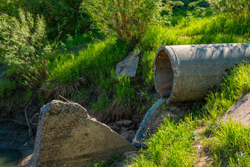 A sewer pipe drains sewage into the city river. Environmental pollution, rivers.