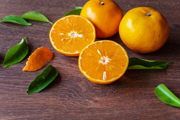 Fresh orange fruit and orange fruit cut in half on a wooden table