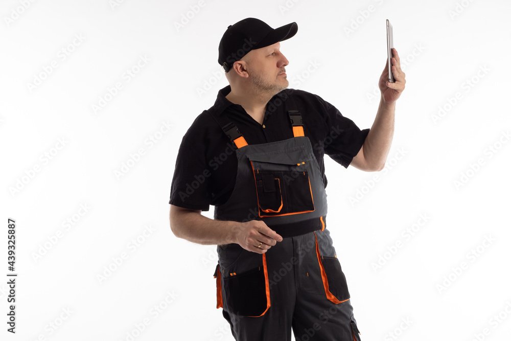 Poster worker man photographing something on tablet computer. studio portrait of repairman. worker man on w