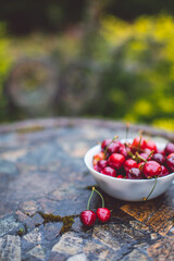 Fresh red ripe organic sweet cherry with waterd drops in a white plate on table in summer garden. closeup