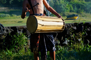 A child is playing a traditional Balinese drum instrument