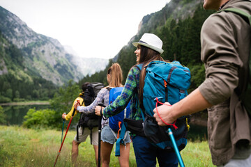 Group of smiling friends hiking with backpacks outdoors. Travel, tourism, hike and people concept.