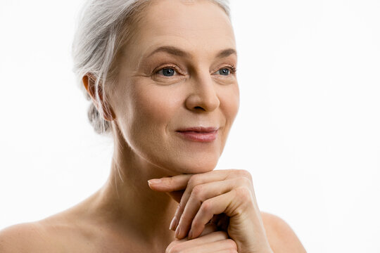 Woman enjoying her perfect skin, holding fingers under the face and smiling
