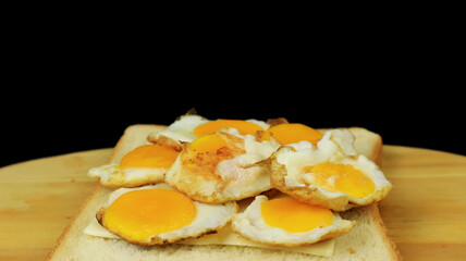 Fresh fried eggs served with bread on a wooden texture. The impression of a dark background makes it exclusive.