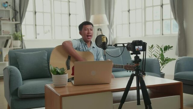 Asian Vlogger With Guitar Talking To Camera. The Boy Is Streaming For His Youtube Channel. The Child Is Broadcasting Live On The Internet
