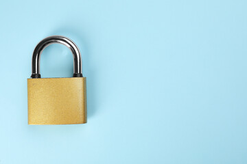 Modern padlock on light blue background, top view. Space for text